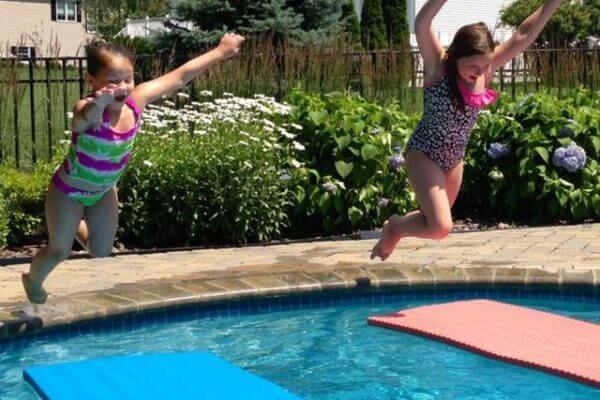 Kids Jumping Into Swimming Pool Over Floats