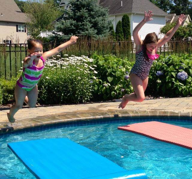 Kids Jumping Into Swimming Pool Over Floats
