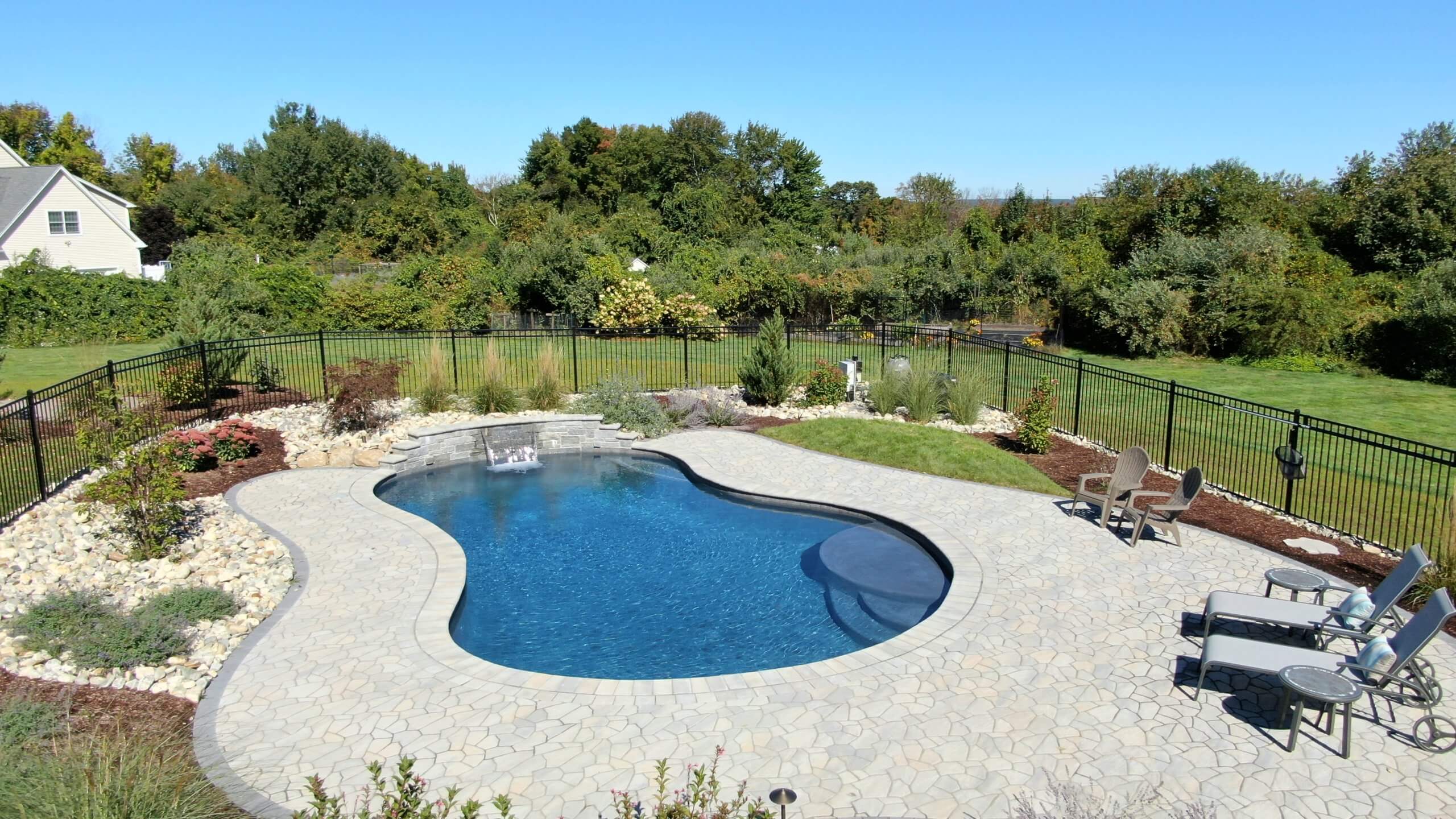 inground gunite pool with patio and waterfall