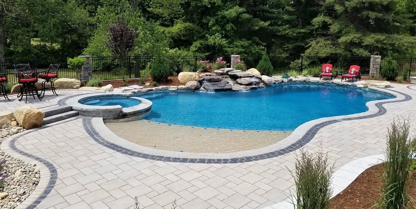 Aqua Pool & Patio gunite swimming pool construction in Connecticut showing swimming pool with attached spa and waterfall