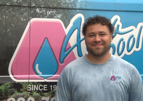 Xayvion Mendez standing in front of an Aqua Pool of CT sign